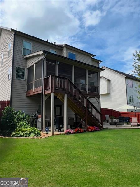 back of house with a yard, a patio area, and a sunroom