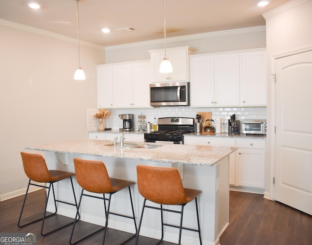 kitchen featuring stainless steel appliances, decorative light fixtures, and an island with sink