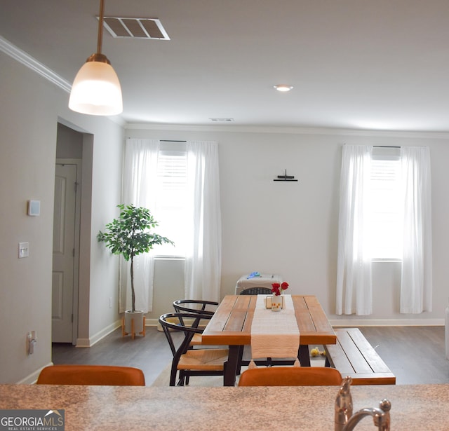 dining area with hardwood / wood-style flooring, ornamental molding, and plenty of natural light