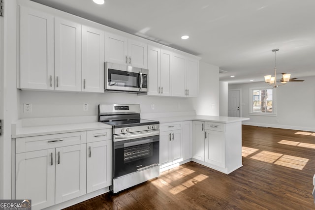 kitchen featuring white cabinetry, decorative light fixtures, appliances with stainless steel finishes, dark hardwood / wood-style flooring, and kitchen peninsula