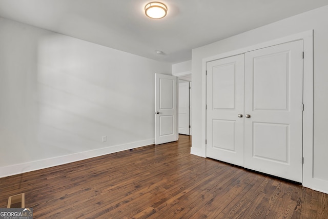 unfurnished bedroom featuring dark hardwood / wood-style floors and a closet