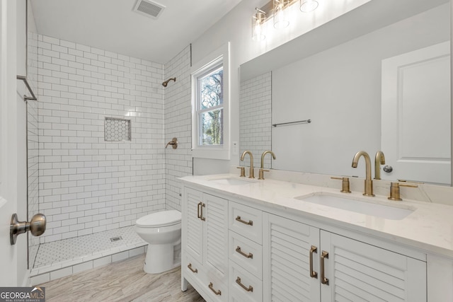 bathroom featuring vanity, toilet, and a tile shower