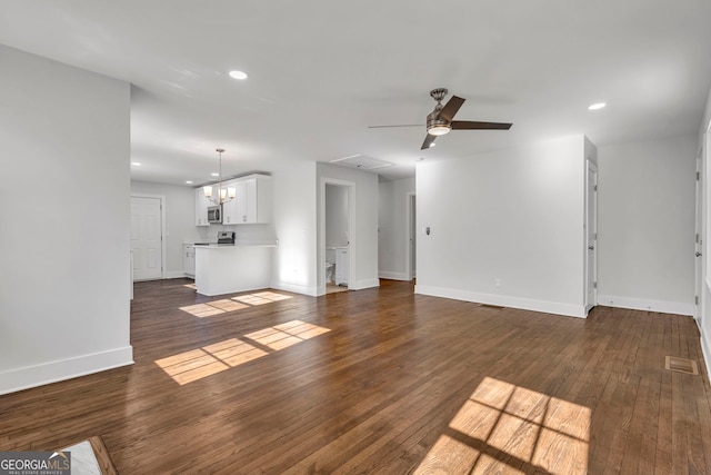 unfurnished living room with dark hardwood / wood-style flooring and ceiling fan with notable chandelier