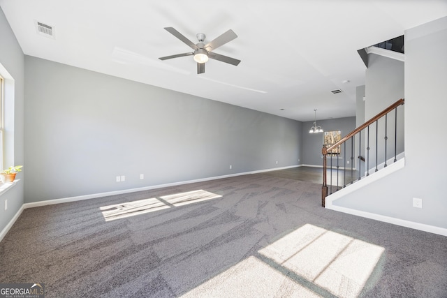 unfurnished living room featuring ceiling fan with notable chandelier and dark colored carpet