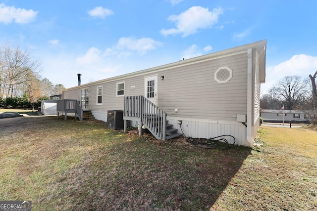 back of property with a wooden deck, a yard, and central AC unit