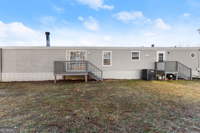 rear view of property featuring a deck, a lawn, and central air condition unit