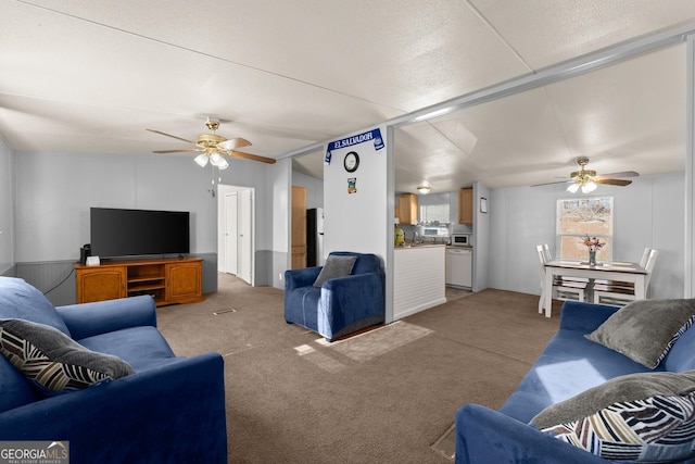 carpeted living room with ceiling fan and vaulted ceiling