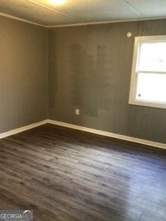 empty room featuring crown molding and dark wood-type flooring