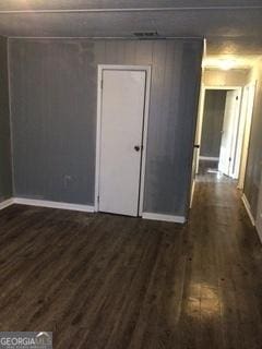 unfurnished room with dark wood-type flooring