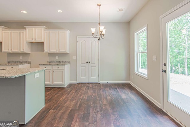 kitchen featuring hanging light fixtures, a notable chandelier, light stone countertops, white cabinets, and dark hardwood / wood-style flooring