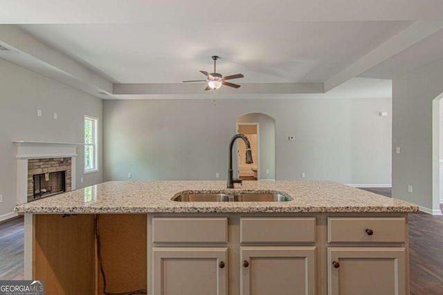 kitchen with sink, a kitchen island with sink, dark hardwood / wood-style floors, and a fireplace