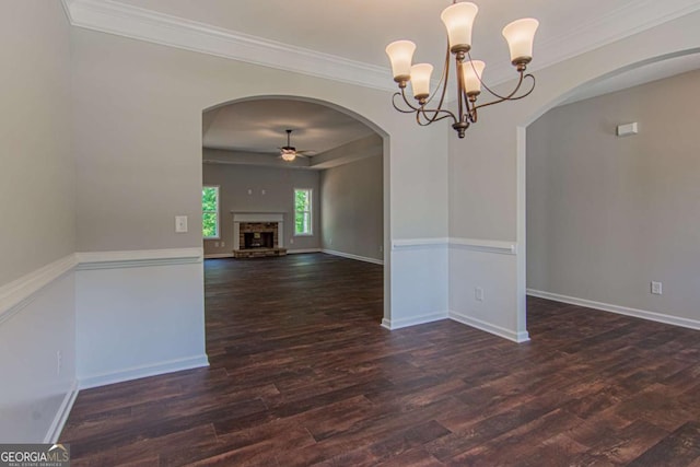 empty room featuring ornamental molding, ceiling fan with notable chandelier, and dark hardwood / wood-style flooring