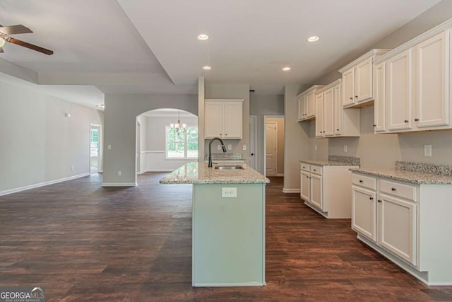 kitchen with sink, white cabinetry, a center island with sink, dark hardwood / wood-style floors, and light stone countertops