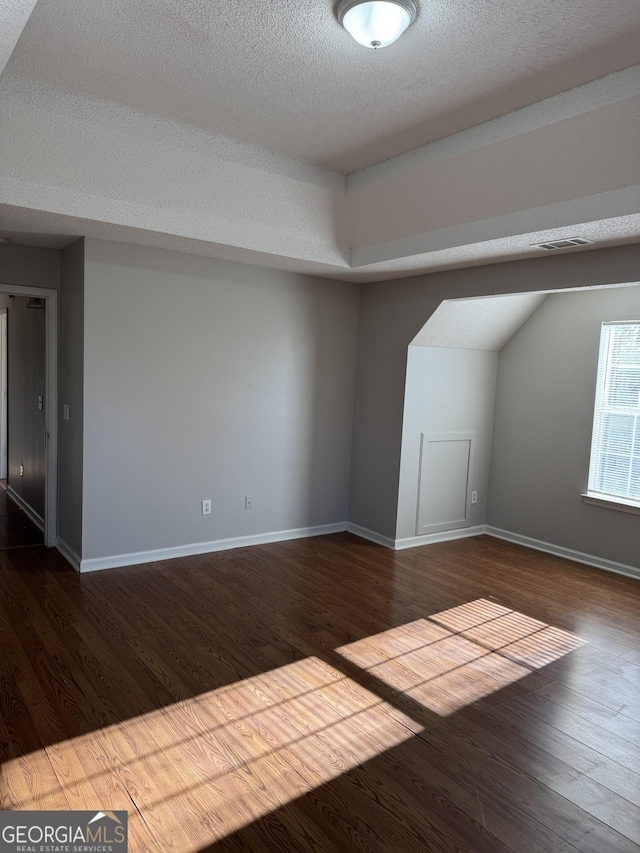 bonus room with wood-type flooring and a textured ceiling