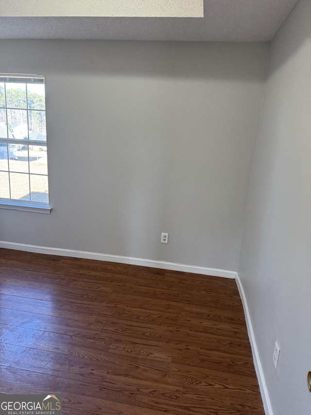 unfurnished room with dark wood-type flooring and a textured ceiling