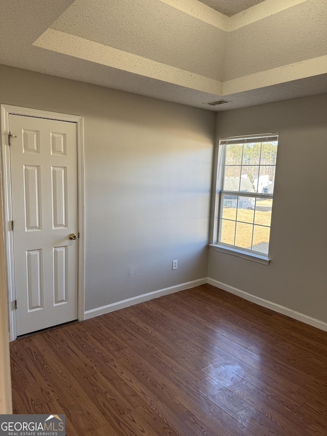 unfurnished room with vaulted ceiling, dark hardwood / wood-style floors, and a textured ceiling