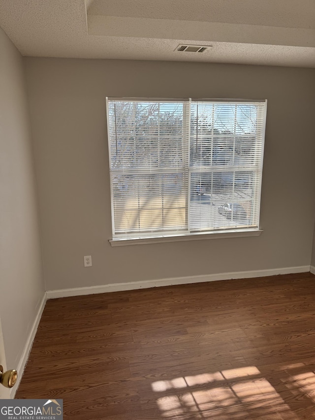 unfurnished room featuring hardwood / wood-style flooring and a textured ceiling