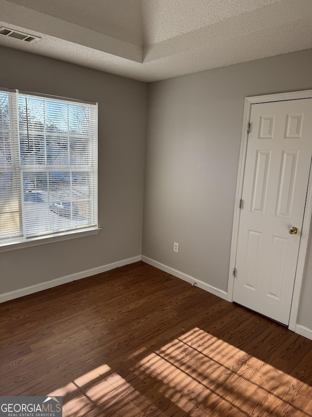 spare room with dark hardwood / wood-style flooring and a textured ceiling