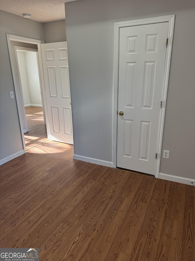 unfurnished room with dark hardwood / wood-style flooring and a textured ceiling