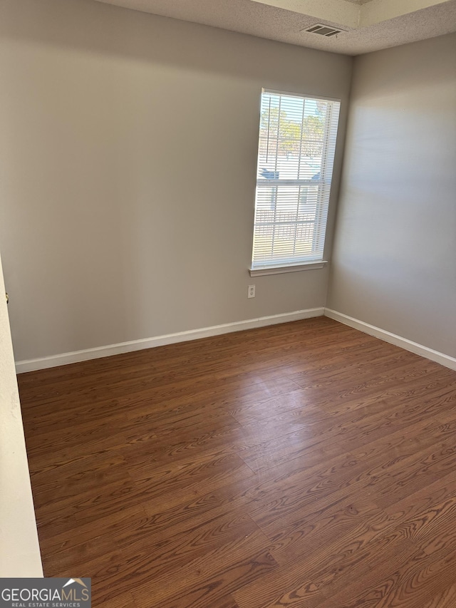 spare room featuring dark wood-type flooring and a textured ceiling