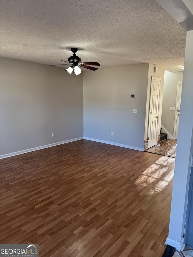 empty room with a textured ceiling, dark wood-type flooring, and ceiling fan