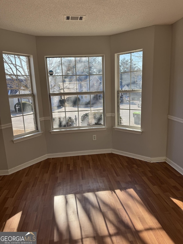 empty room with dark wood-type flooring and a textured ceiling