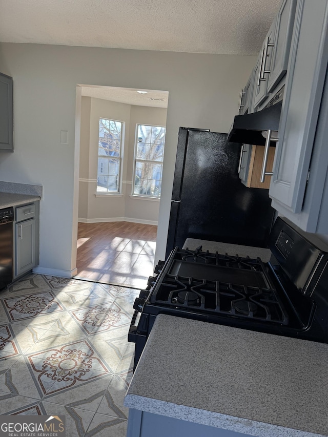 kitchen with black fridge, range with gas cooktop, gray cabinets, and a textured ceiling