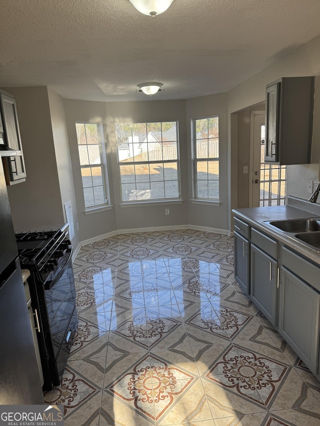 kitchen with black gas stove, sink, gray cabinetry, and a textured ceiling