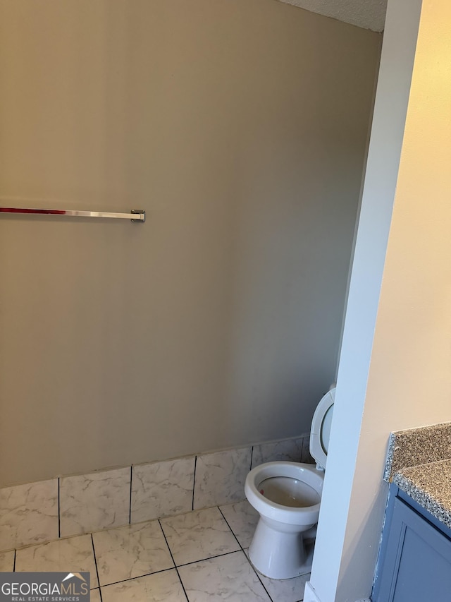 bathroom featuring vanity, toilet, tile patterned flooring, and a textured ceiling