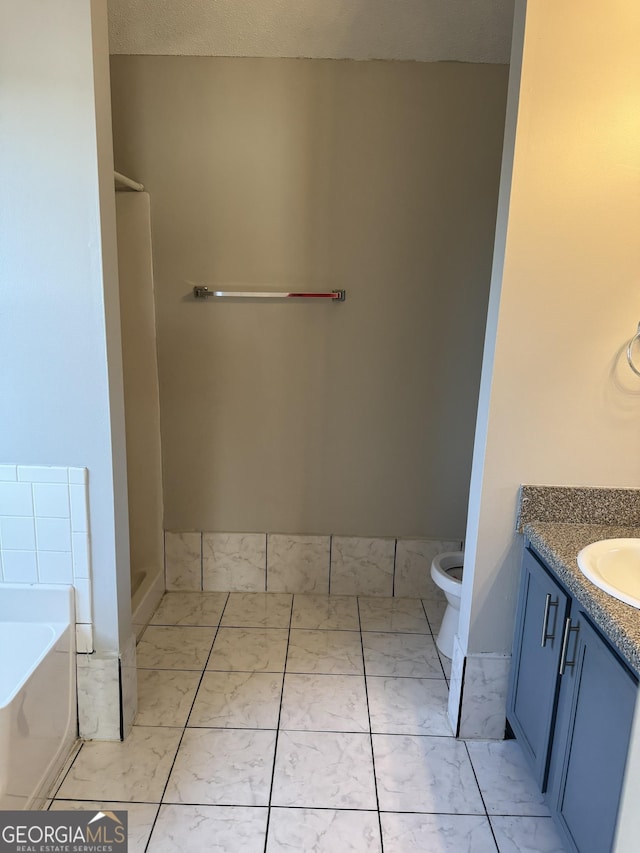 bathroom featuring tile patterned flooring, vanity, a bathing tub, and toilet