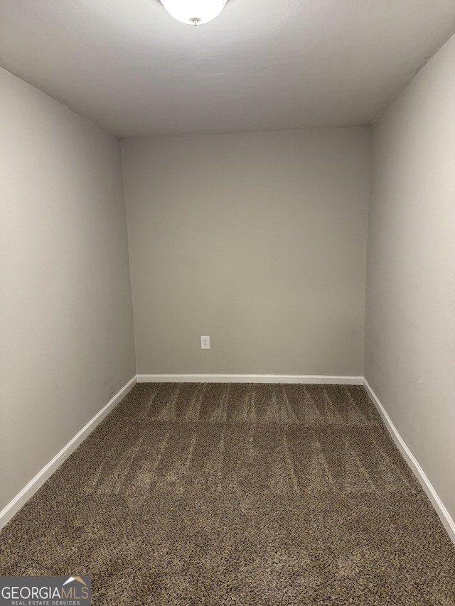 spare room featuring dark carpet