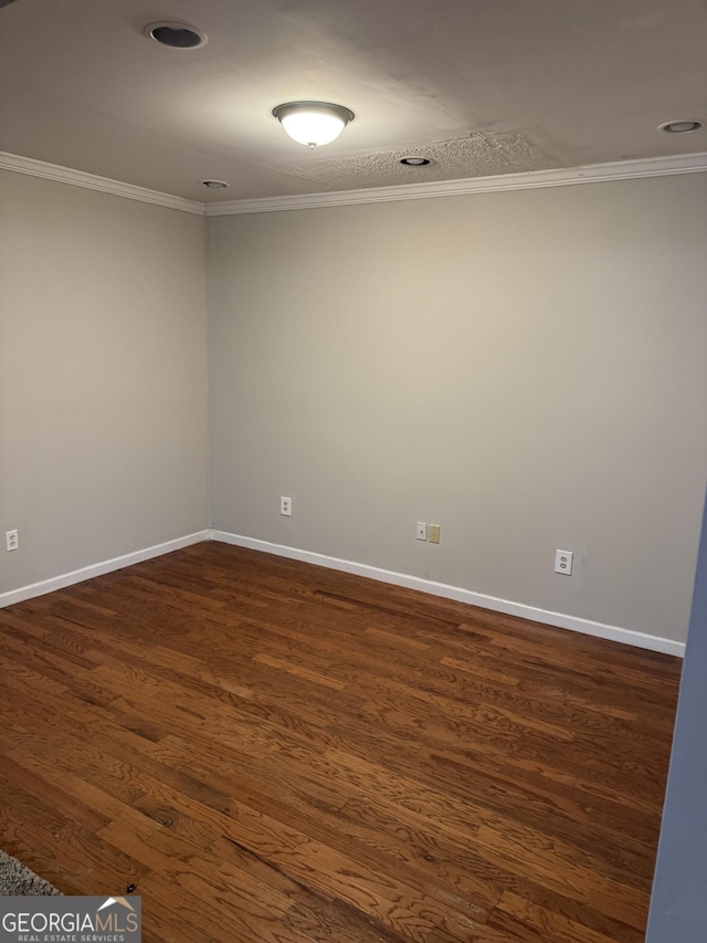 spare room with ornamental molding and dark wood-type flooring