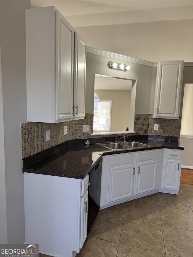 kitchen featuring sink, white cabinetry, tasteful backsplash, light tile patterned floors, and black dishwasher