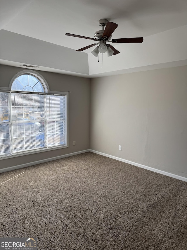 carpeted empty room with ceiling fan and a tray ceiling