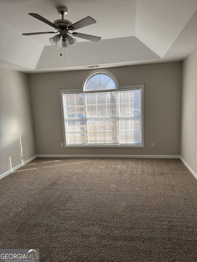 empty room with carpet floors, ceiling fan, and a tray ceiling