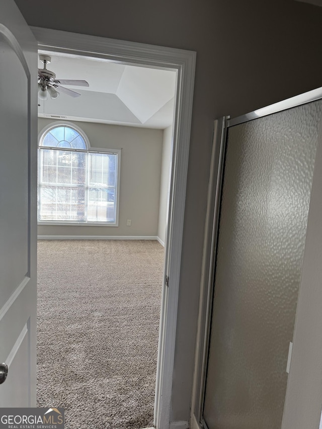 bathroom with an enclosed shower, ceiling fan, and a tray ceiling