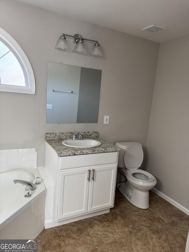 bathroom with toilet, vanity, and a bath