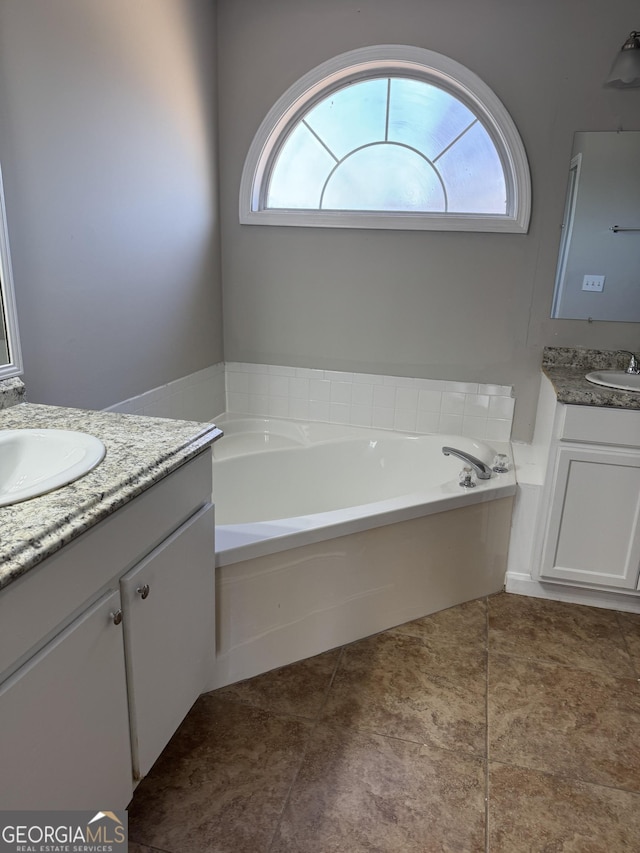 bathroom with tile patterned flooring, vanity, a tub, and a healthy amount of sunlight