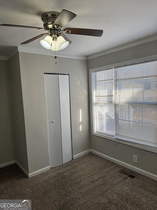 unfurnished bedroom featuring crown molding, ceiling fan, a closet, and carpet