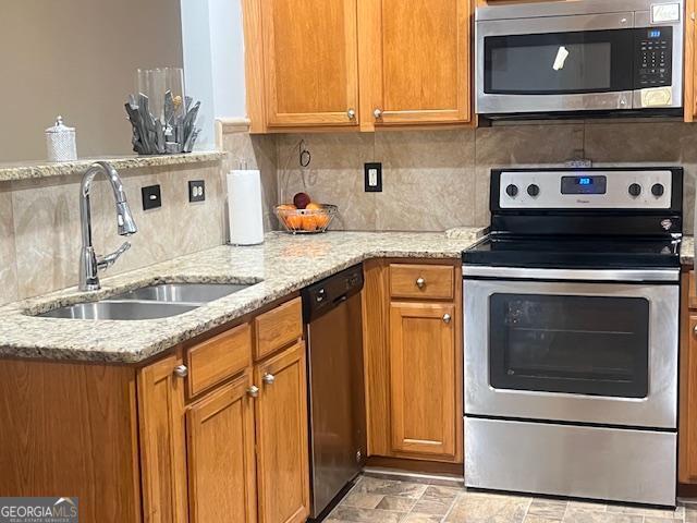 kitchen featuring sink, decorative backsplash, stainless steel appliances, and light stone countertops