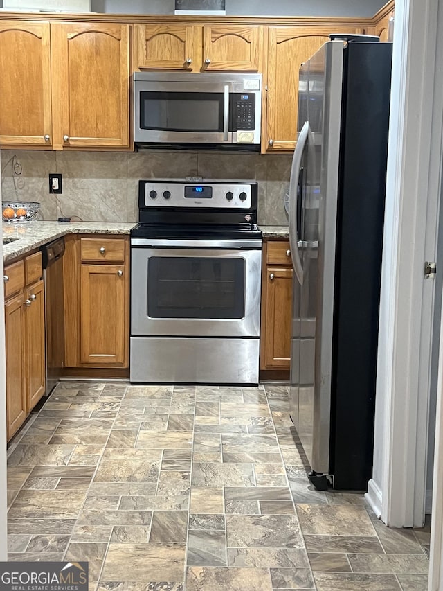 kitchen featuring tasteful backsplash, appliances with stainless steel finishes, and light stone countertops