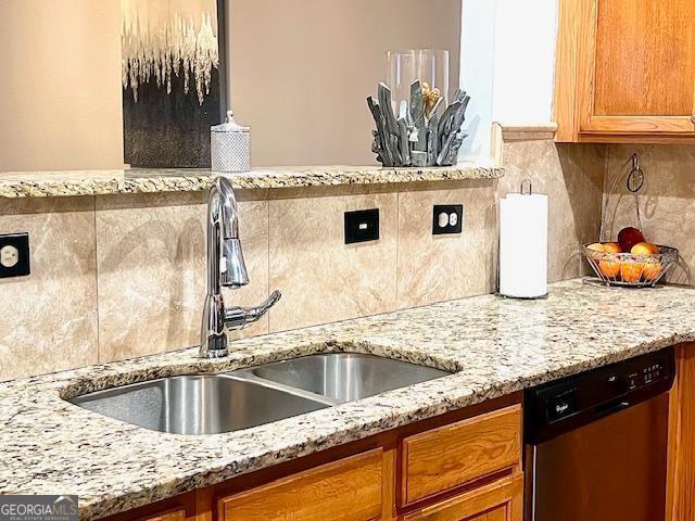 kitchen with dishwasher, light stone countertops, sink, and decorative backsplash