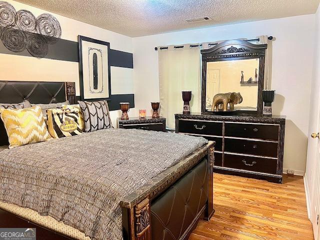 bedroom with wood-type flooring and a textured ceiling