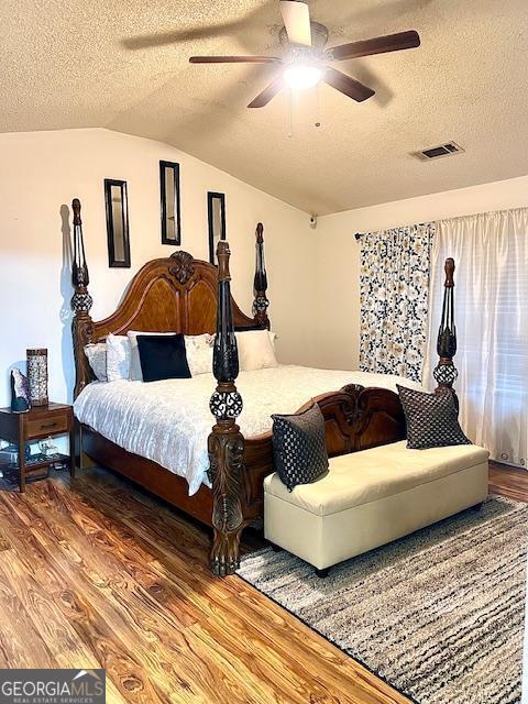 bedroom featuring vaulted ceiling, wood-type flooring, a textured ceiling, and ceiling fan