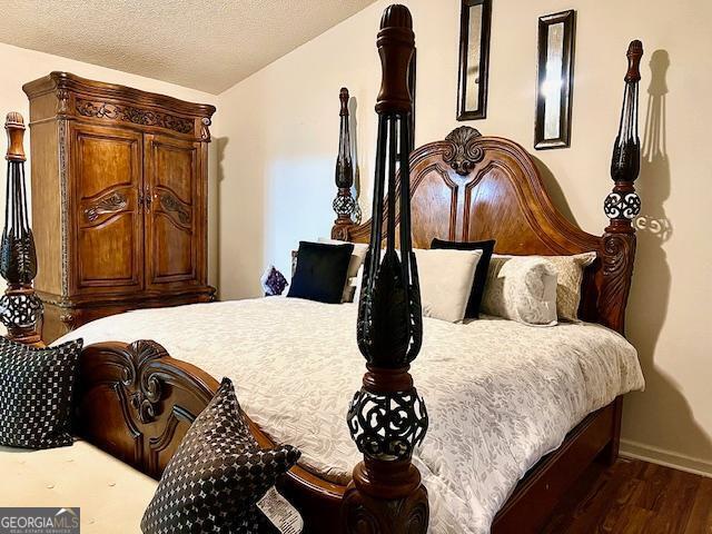 bedroom with hardwood / wood-style flooring, lofted ceiling, and a textured ceiling