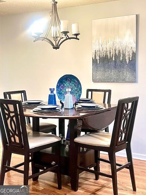 dining area with hardwood / wood-style flooring, a textured ceiling, and a notable chandelier