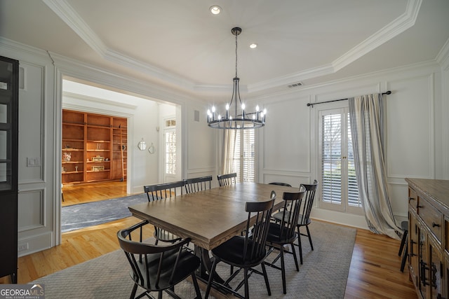 dining room featuring an inviting chandelier, hardwood / wood-style floors, crown molding, and built in shelves