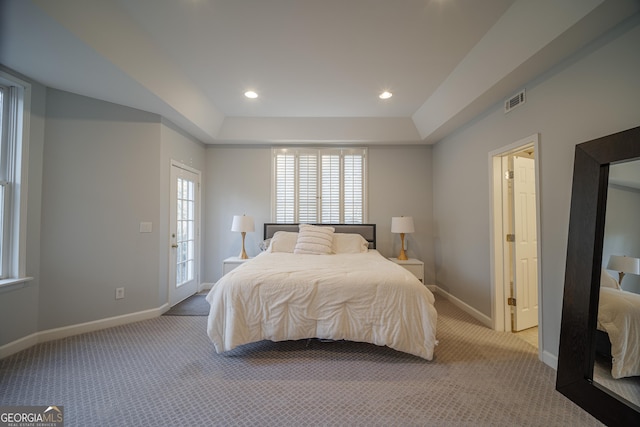 carpeted bedroom with a tray ceiling