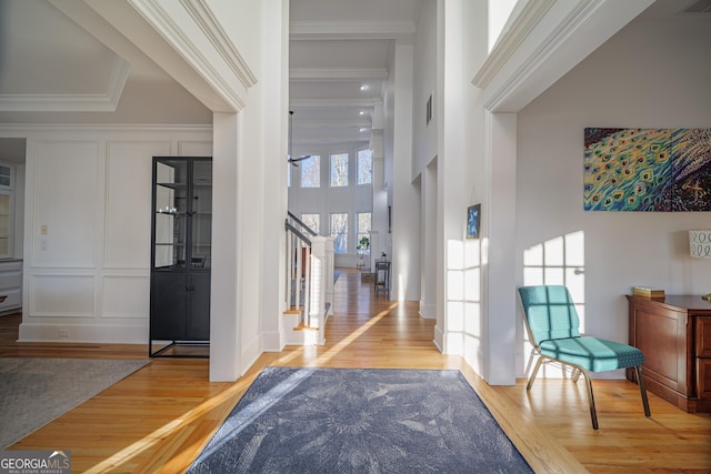 foyer with hardwood / wood-style flooring, ornamental molding, and a high ceiling