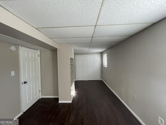 hallway with dark hardwood / wood-style flooring and a paneled ceiling